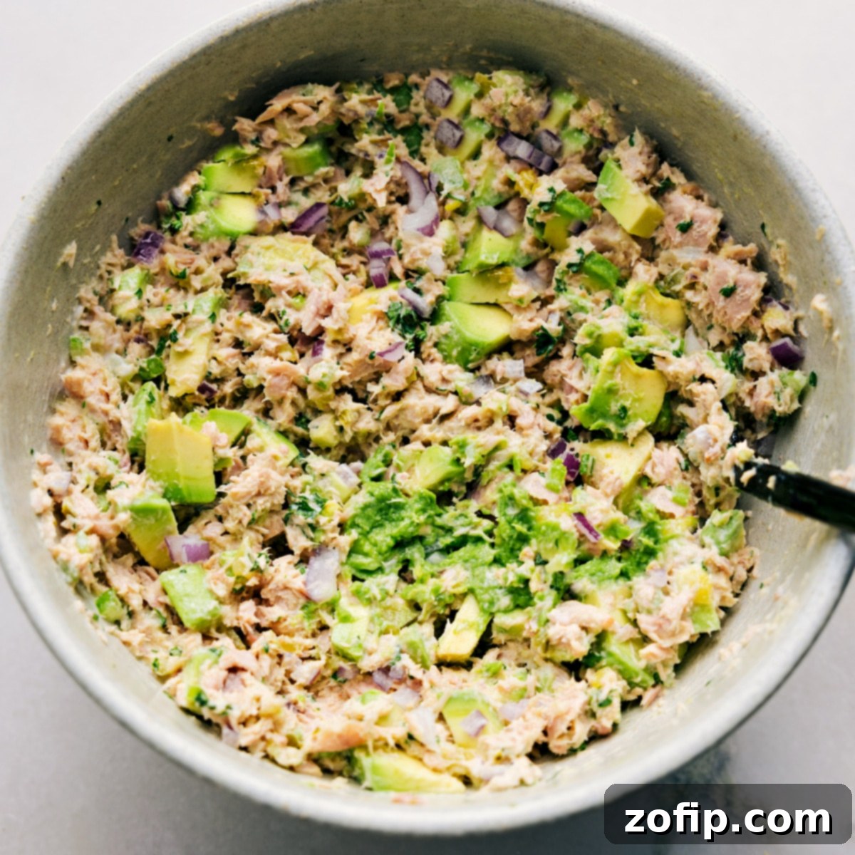 The Avocado Tuna Salad is perfectly tossed in a vibrant bowl, showcasing its creamy texture and chunky avocado pieces, ready to be served as a delicious sandwich or enjoyed in any preferred way.