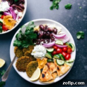 Healthy Baked Falafel 3 Baked falafel served on a plate with pita bread, tzatziki sauce, olives, onions, tomatoes, and cucumbers.