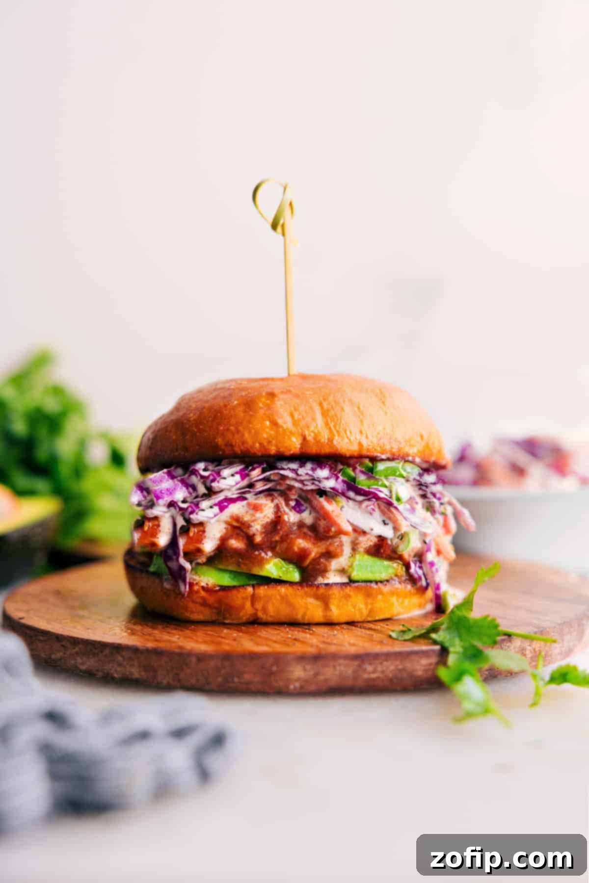 Crockpot BBQ Chicken on a bun, topped with slaw and avocado.