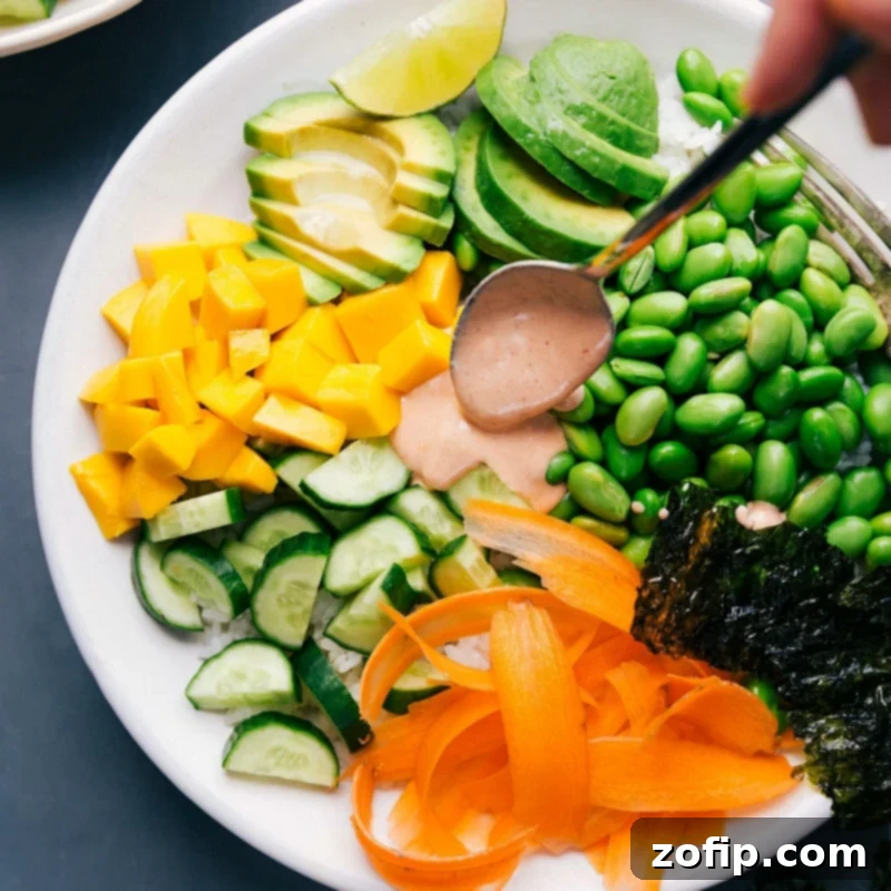 Deconstructed Sushi Bowls 3 Spicy sriracha mayo being drizzled generously over a colorful vegetarian sushi bowl, enhancing its appeal.