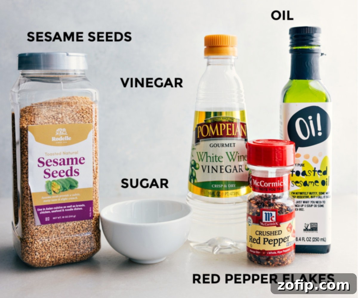 The components of the flavorful sesame dressing for Asian Cucumber Salad laid out: distinct bowls of sesame oil, white wine vinegar, granulated sugar, and toasted sesame seeds, all ready for mixing.