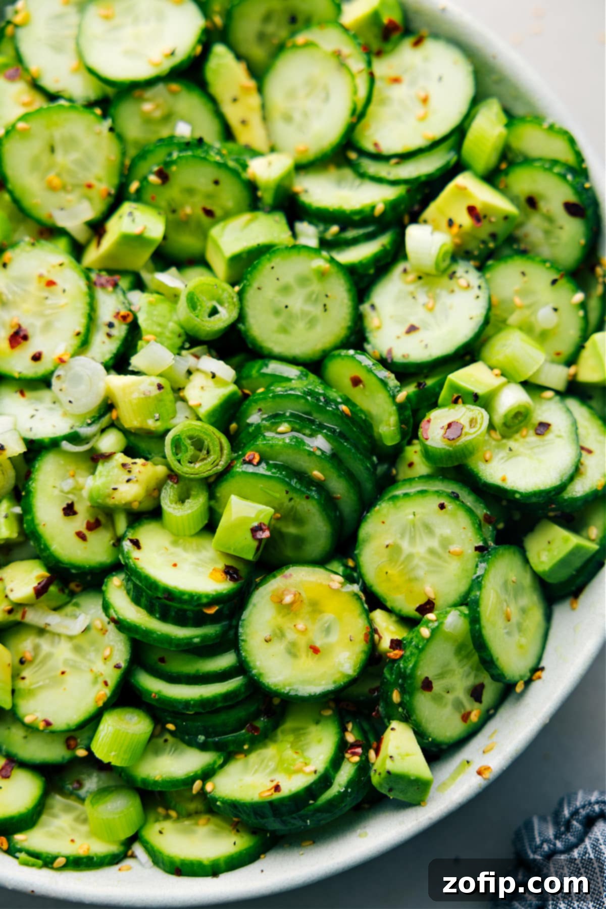 A close-up shot of the Asian Cucumber Salad in a decorative bowl, perfectly dressed and tossed, showcasing the beautiful mix of cucumbers, avocado, and green onions. Ideal as a light and healthy side dish for any occasion.