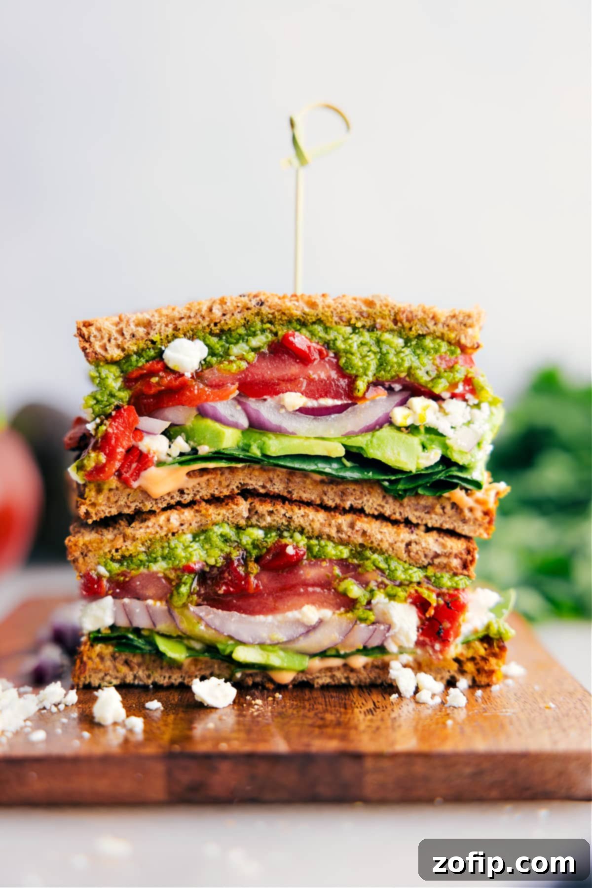 A beautifully assembled easy, vegetarian Mediterranean Sandwich with layers of fresh ingredients, creamy feta cheese, and basil pesto on hearty bread.