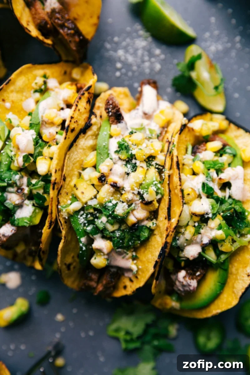 Finished steak taco recipe, with tacos artfully arranged side by side, generously stuffed with delicious meat, vibrant corn salsa, and various toppings.