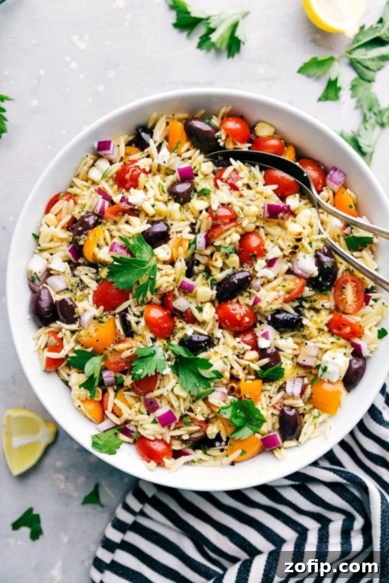 Healthy Orzo Pasta Salad - Ready to Serve in a Bowl Delicious and healthy orzo pasta salad in a bowl with spoons, ready to be served.