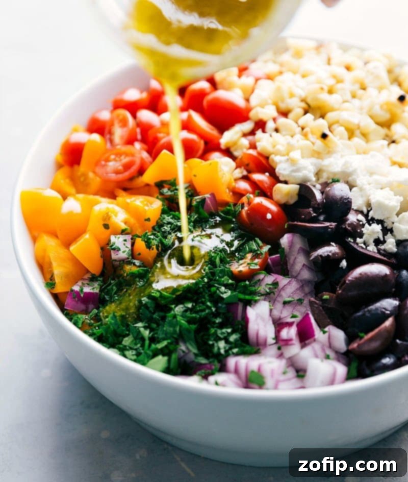 Adding Lemon Dressing to Greek Orzo Pasta Salad with Feta - Flavor Enhancement Lemon dressing being poured over the ingredients of the greek orzo pasta salad with feta, enhancing the flavors.
