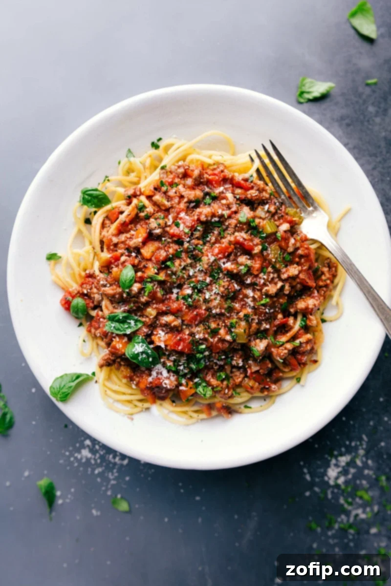 Savory and delicious turkey bolognese on a bed of spaghetti, topped with fresh herbs.