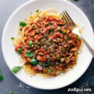 Savory and delicious turkey bolognese on a bed of spaghetti, topped with fresh herbs.