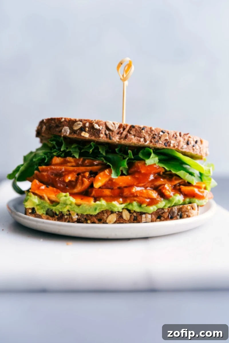 The delicious and stuffed BBQ chicken sandwich, ready to be devoured, with layers of chicken, avocado, and lettuce between toasted bread.