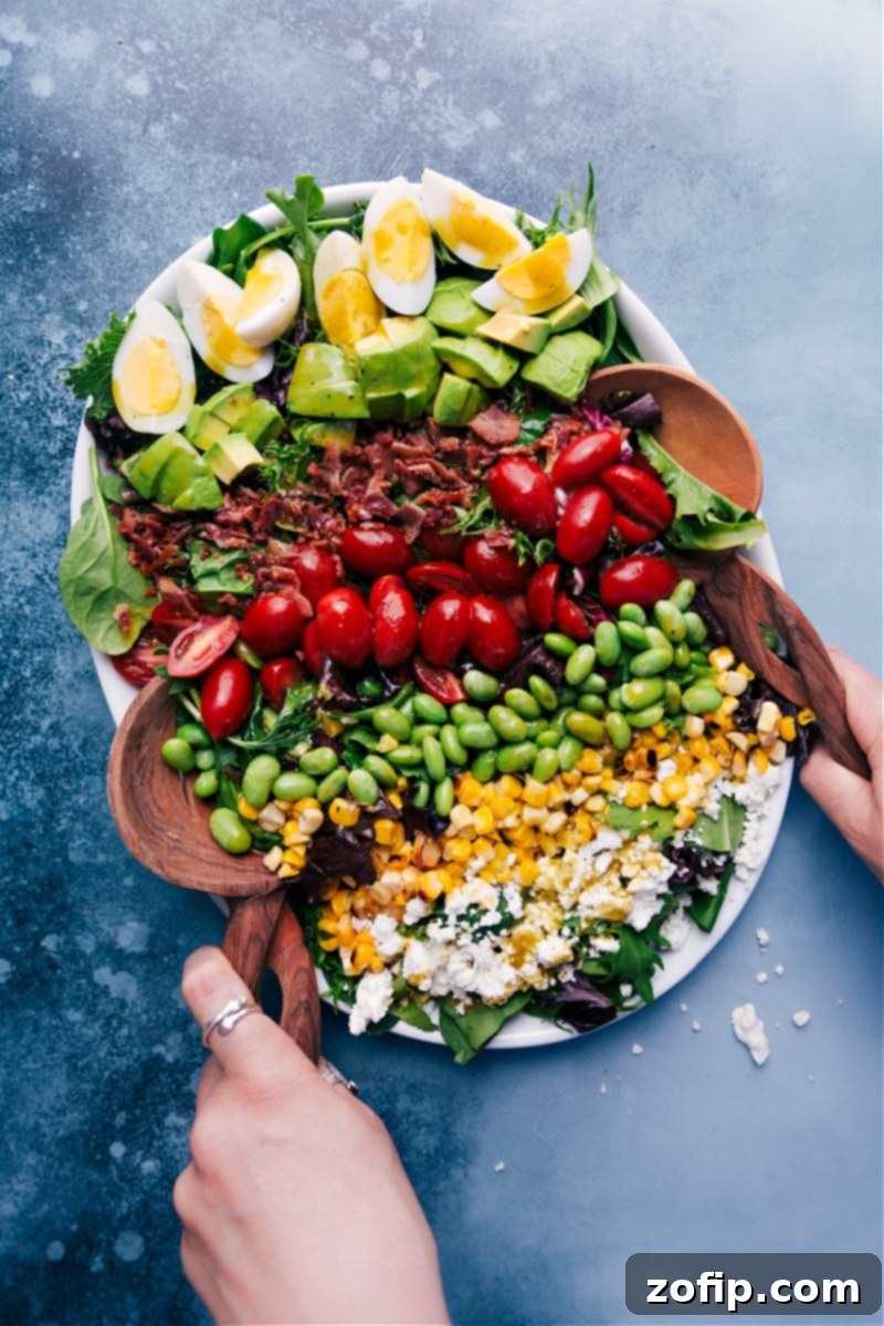Vibrant Cobb Salad featuring hard-boiled eggs, creamy avocado, crisp bacon, and fresh vegetables drizzled with a homemade herbed vinaigrette.