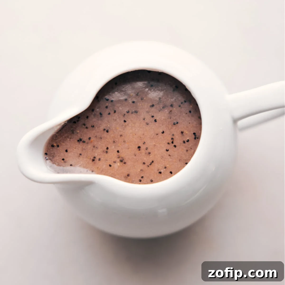 Delicious Poppyseed Dressing A close-up of the creamy, homemade poppyseed dressing in a clear dressing dispenser, ready to be poured over salad.