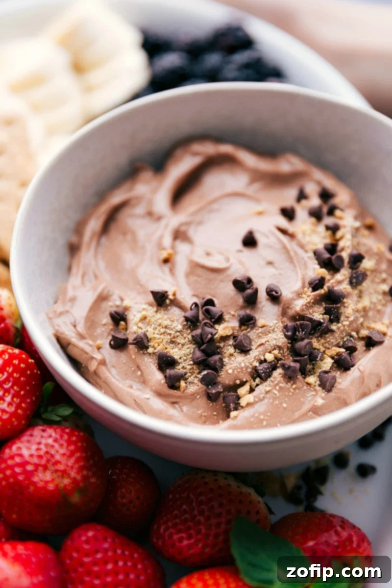 Close-up of creamy chocolate fruit dip generously garnished with crumbled graham cracker and miniature chocolate chips, ready for dipping a variety of fresh fruits and sweet treats.