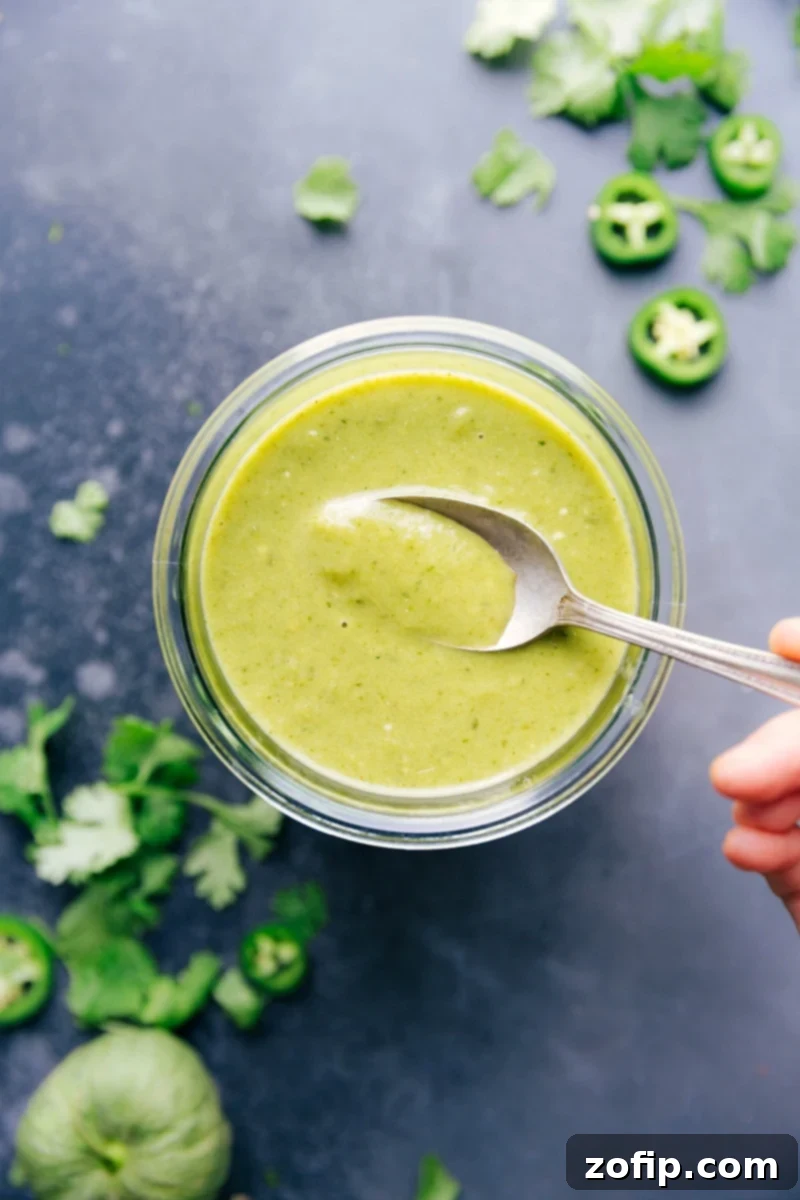 Homemade Green Enchilada Sauce: So much flavor you'll never reach for canned sauce again! This easy recipe features roasted tomatillos, onion, peppers, and garlic, enhanced with seasonings, vegetable broth, and olive oil. Perfect for any Mexican dish. #enchiladas #greensauce #greenenchiladas #tomatillos #mexican #spicy #tacotuesday Freshly made homemade green enchilada sauce in a glass jar, ready for use.