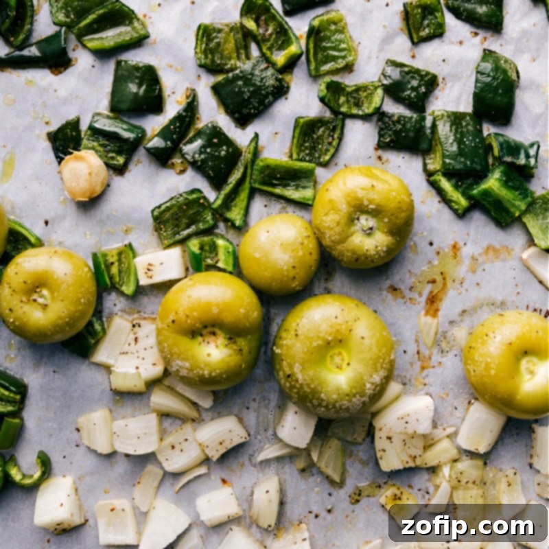 This easy homemade green enchilada sauce begins with perfectly roasted tomatillos, peppers, onions, and garlic, creating a foundation of rich, deep flavor. We then blend in seasonings, vegetable broth, and olive oil for the ultimate taste. Recipe via ChelseasMessyApron.com #enchiladas #greensauce #greenenchiladas #tomatillos #mexican #spicy #tacotuesday A sheet pan filled with perfectly roasted tomatillos, peppers, onions, and garlic, fresh out of the oven, destined for homemade green enchilada sauce.