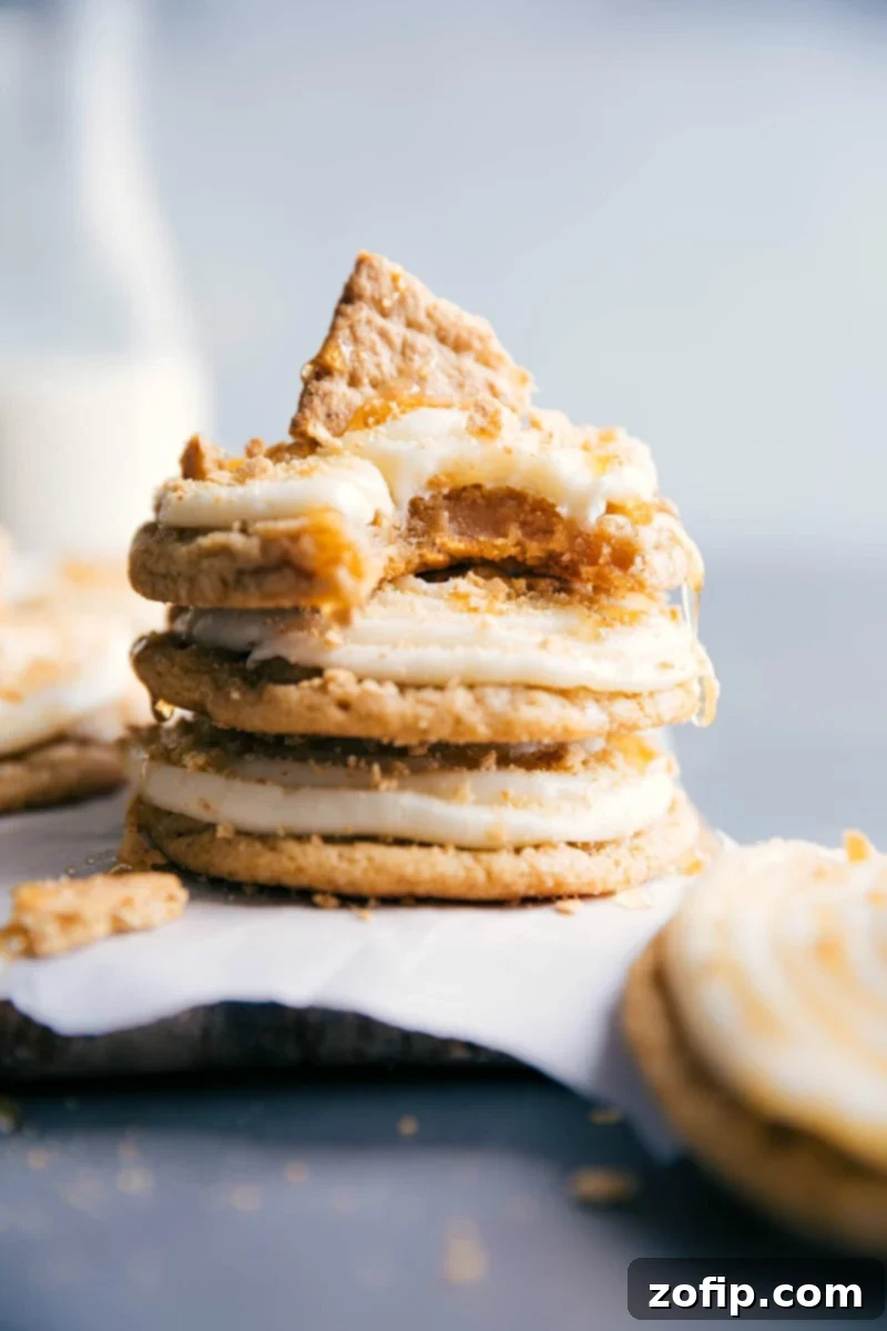 Stacked Frosted Honey Graham Cookies Several frosted honey graham cookies stacked up, topped with graham cracker crumbs, with a bite taken from the top cookie, revealing the soft interior.