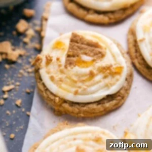 Garnished Frosted Honey Graham Cookies Frosted honey graham cookies topped with creamy frosting, garnished with graham cracker crumbs, a drizzle of honey, and a large graham cracker piece.