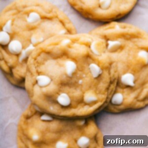 The completed recipe for cornmeal cookies, with white chocolate chips scattered around them, showcasing a warm and delectable treat.