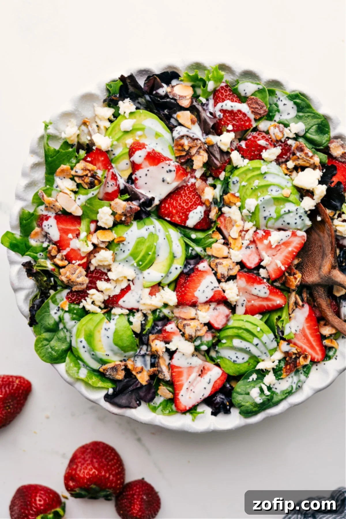 Colorful and Fresh Strawberry Poppy Seed Salad Vibrant Strawberry Poppyseed Salad in a large serving bowl, drizzled generously with homemade poppyseed dressing, ready to be enjoyed.