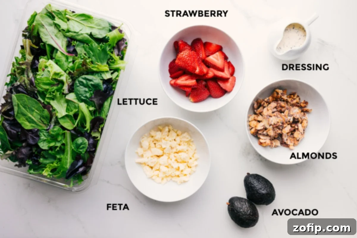 Ingredients In Strawberry Poppyseed Salad Recipe All the fresh ingredients for Strawberry Poppyseed Salad, including greens, sliced strawberries, diced avocado, crumbled feta, and candied almonds, laid out for preparation.