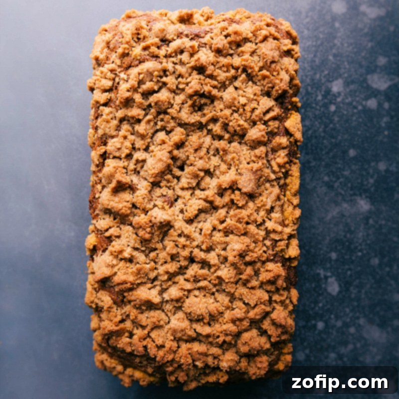 Delicious Pumpkin Bread with Crispy Streusel Topping A freshly baked loaf of pumpkin bread showcasing its golden-brown, crispy streusel topping, ready to be sliced and served.