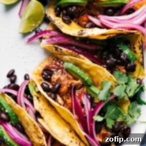 Finished chipotle chicken tacos, ready to eat, topped with fresh cilantro, pickled onions, and other toppings.