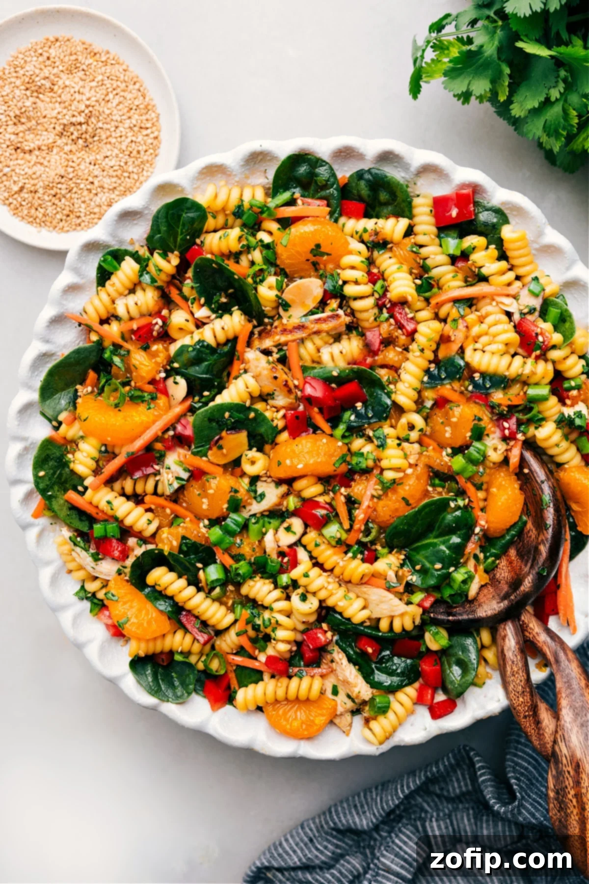 The Best Asian Pasta Salad Recipe A vibrant Asian Pasta Salad, beautifully tossed and dressed, presented in a large, inviting ceramic bowl. It features colorful vegetables, tender pasta, and a rich, glossy dressing.