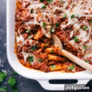 Ultimate Baked Ziti 5 Finished baked ziti in a casserole dish, with a scoop taken out to reveal the warm, flavor-packed layers inside.