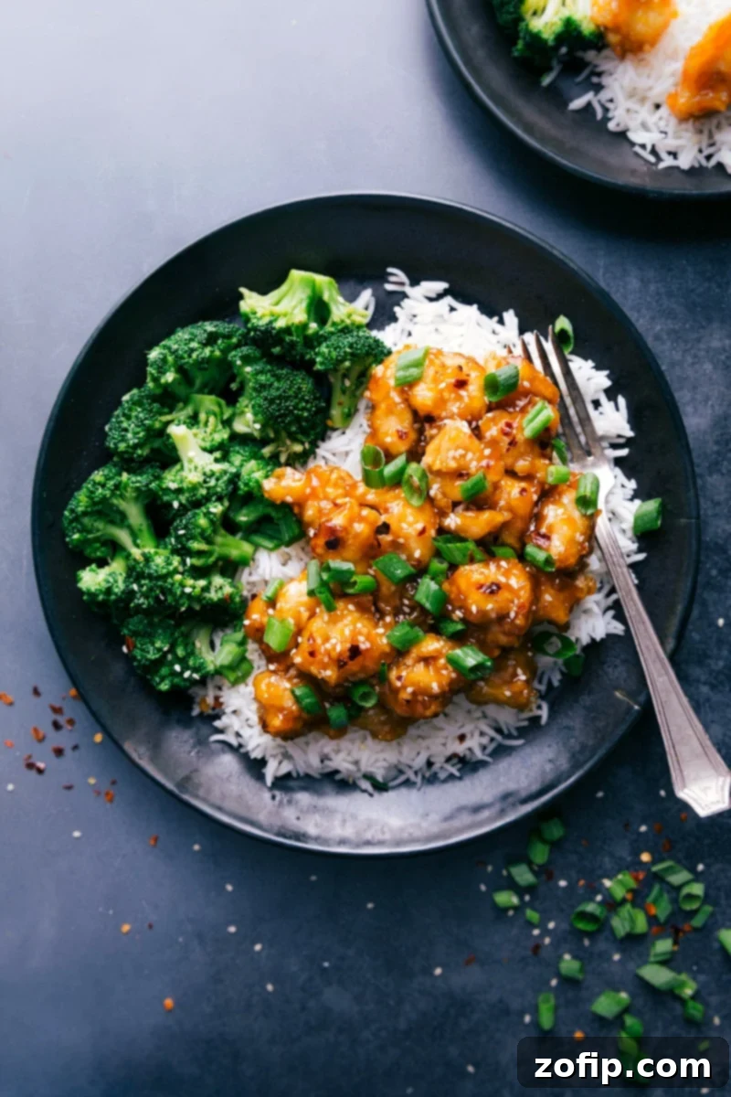 Delicious Orange Chicken served with fluffy white rice and fresh steamed broccoli, garnished with sesame seeds and green onions.