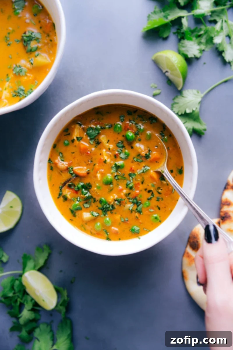 Vibrant and healthy chicken curry soup in a bowl, topped with fresh herbs and ready to be enjoyed.