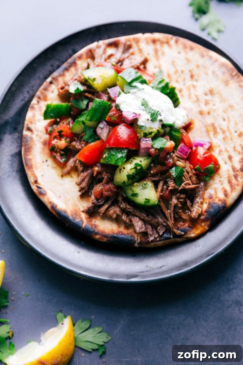 Juicy beef gyro on soft pita bread, topped with crisp fresh vegetables and a generous drizzle of tangy sauce, creating a flavorful and satisfying meal.