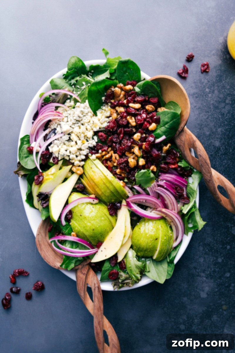 A beautifully arranged pear salad on a rustic wooden tray, garnished and ready to be served.