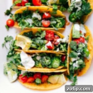 Baked chicken tacos fresh out of the oven, topped with fresh vegetables, herbs, and a delicious sauce.