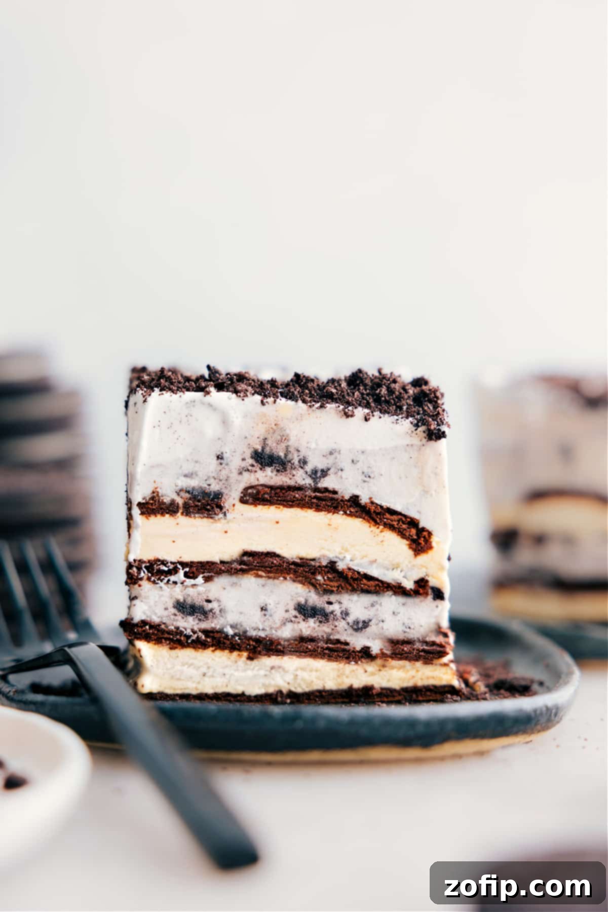 Ice Cream Sandwich Dream 2 A perfectly sliced piece of the four-ingredient Ice Cream Sandwich Cake, showcasing the distinct layers of ice cream sandwiches, cookies-and-cream ice cream, and whipped cream topping generously sprinkled with crushed Oreos.