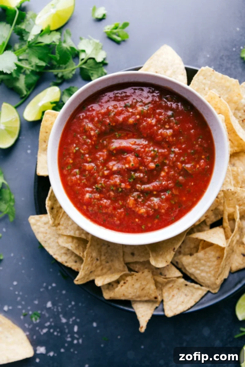 A big bowl of delicious homemade salsa, packed with vibrant red and green flavors, perfectly paired with a pile of golden, crispy tortilla chips ready for dipping.