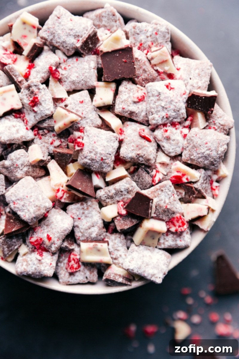 A close-up shot of Chex mix muddy buddies with peppermint bark, a delicious and festive snack, generously coated in powdered sugar and crushed peppermint, glistening and ready to be enjoyed by everyone during the holidays.