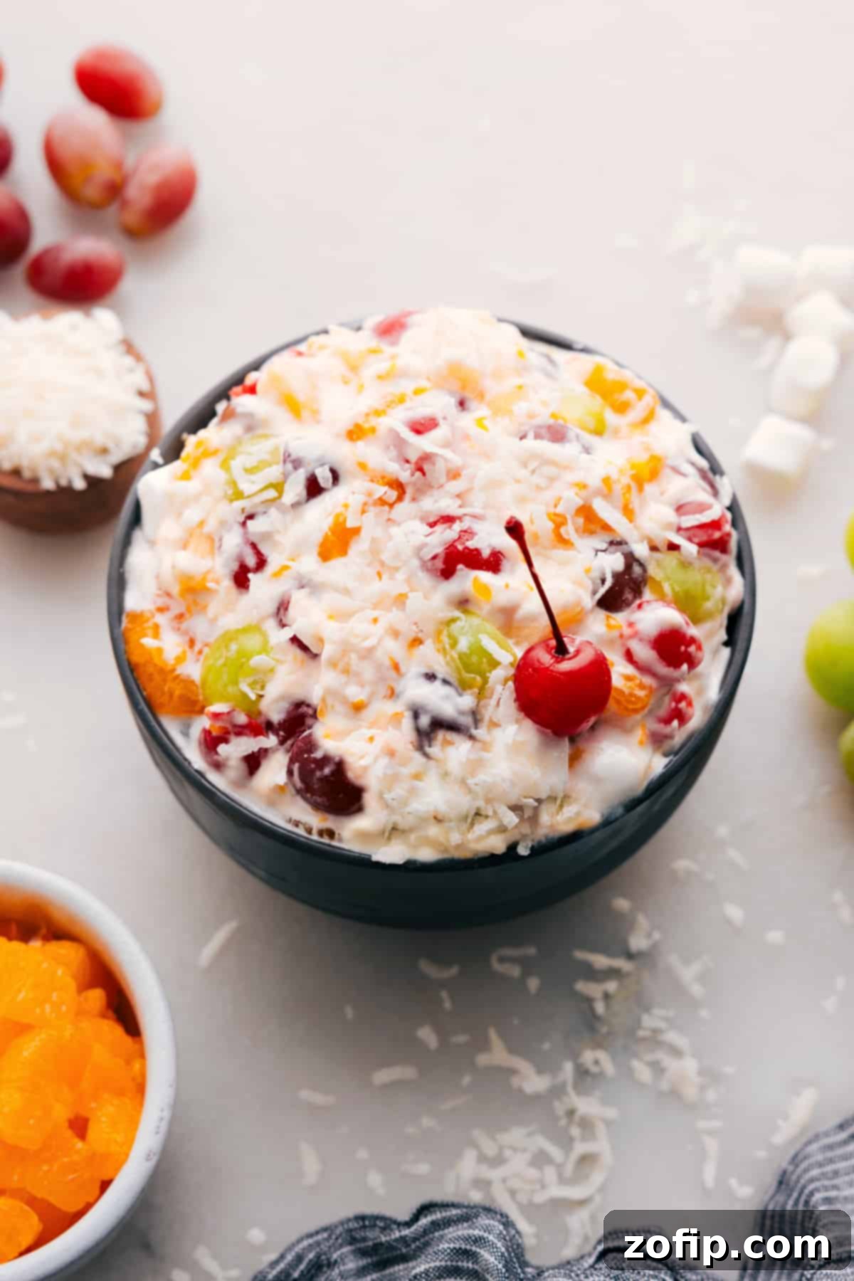 The Best Ambrosia Salad Recipe: A Classic Creamy Fruit Dessert A beautiful bowl of Ambrosia Salad, garnished with a bright red maraschino cherry on top, ready to be served.