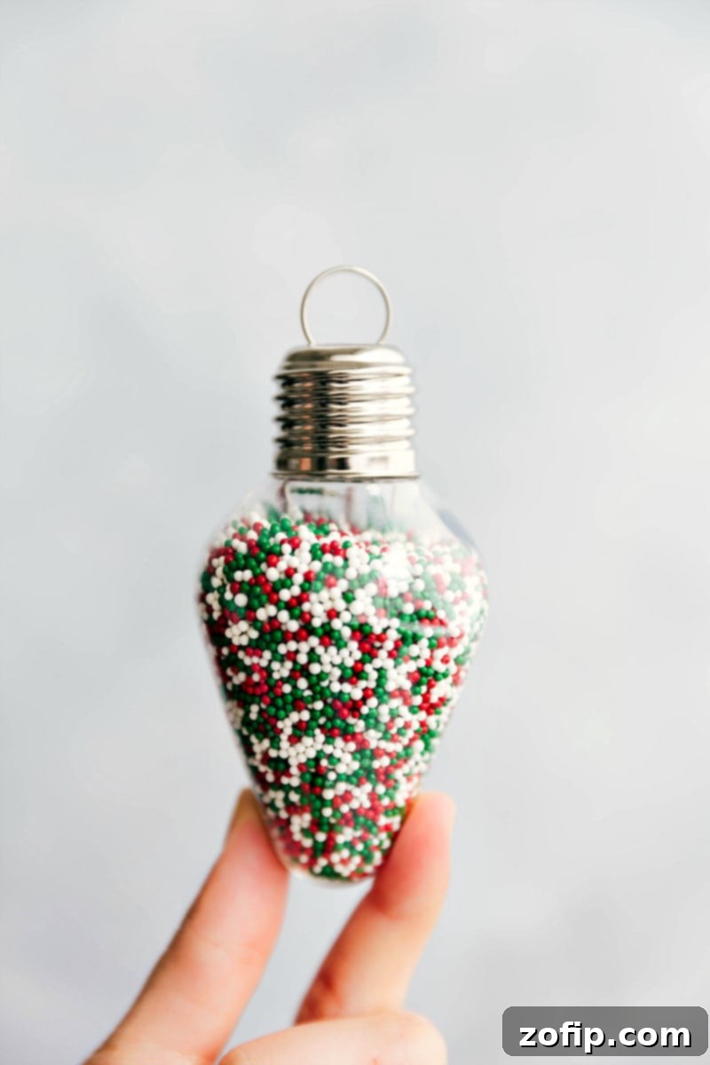 Close-up of vibrant Christmas sprinkles elegantly presented in an ornament-shaped jar, ready for a DIY sugar cookie kit.
