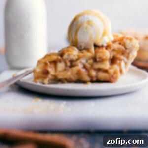 Slice of apple pie with ice cream and caramel sauce on top.