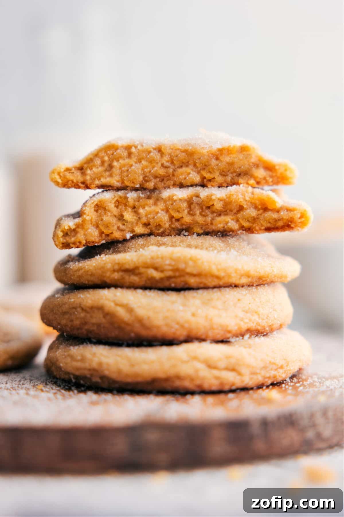 Stacked brown sugar cookies, with one broken in half revealing its soft, chewy interior and golden-brown hue.
