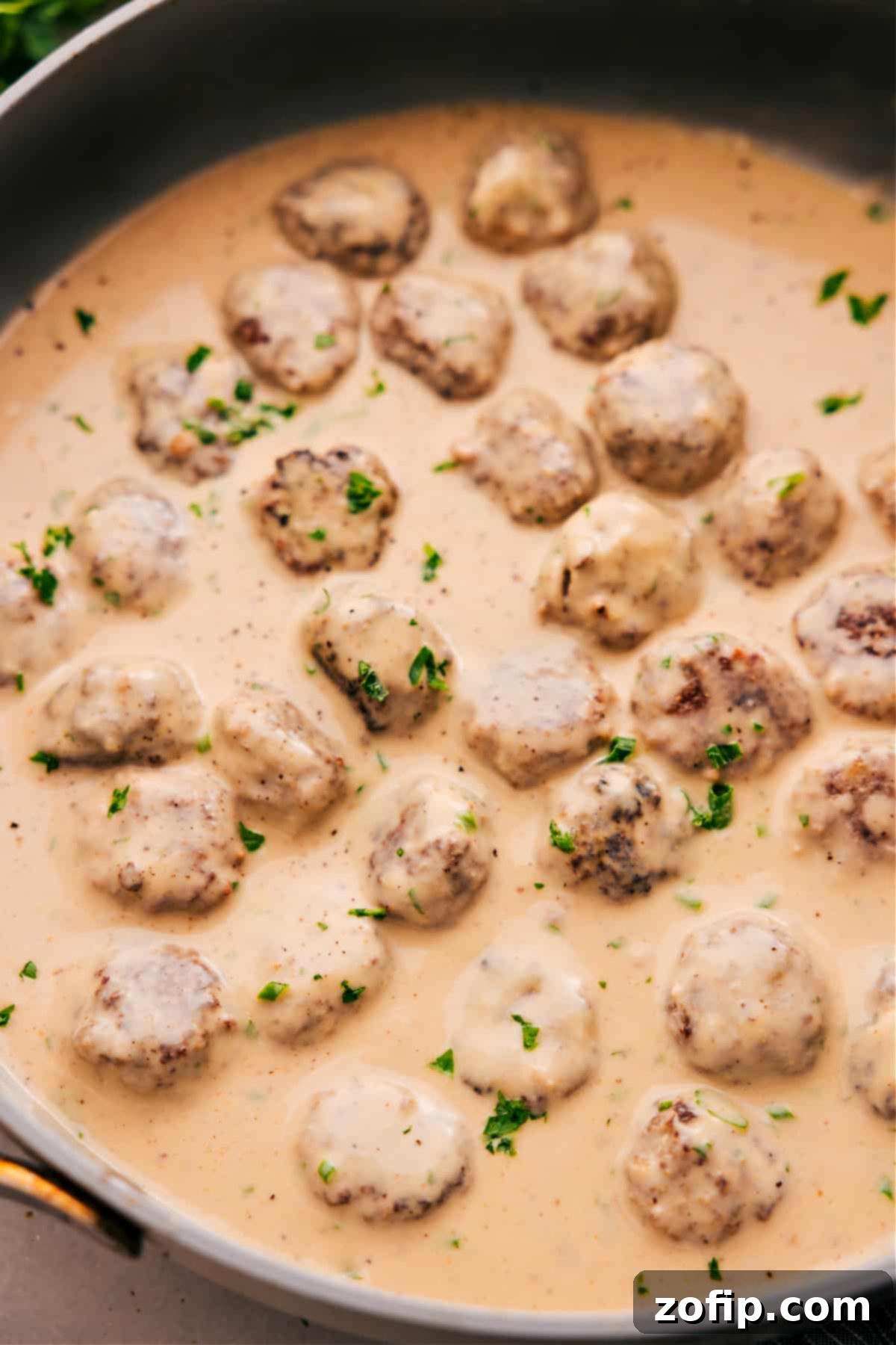 Delicious One-Skillet Swedish Meatballs with Rich Gravy Close-up of Swedish meatballs covered in creamy gravy, garnished with fresh parsley and ready to be served.