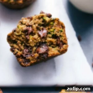 Moist Gluten-Free Zucchini Muffins 3 Gluten-free zucchini muffins, with one split open to show the insides revealing the fluffy muffin, zucchini, and melted chocolate chips.