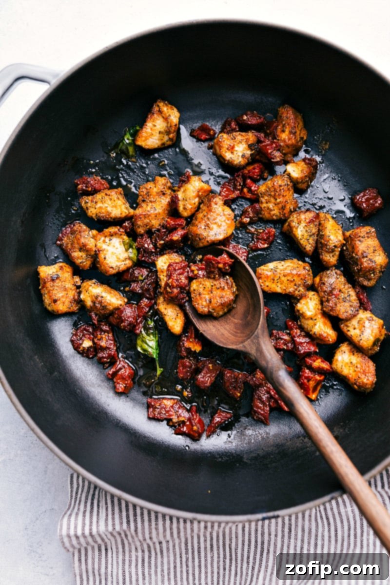 Process shot-- Overhead image of the chicken and sun-dried tomatoes being cooked in the pot.