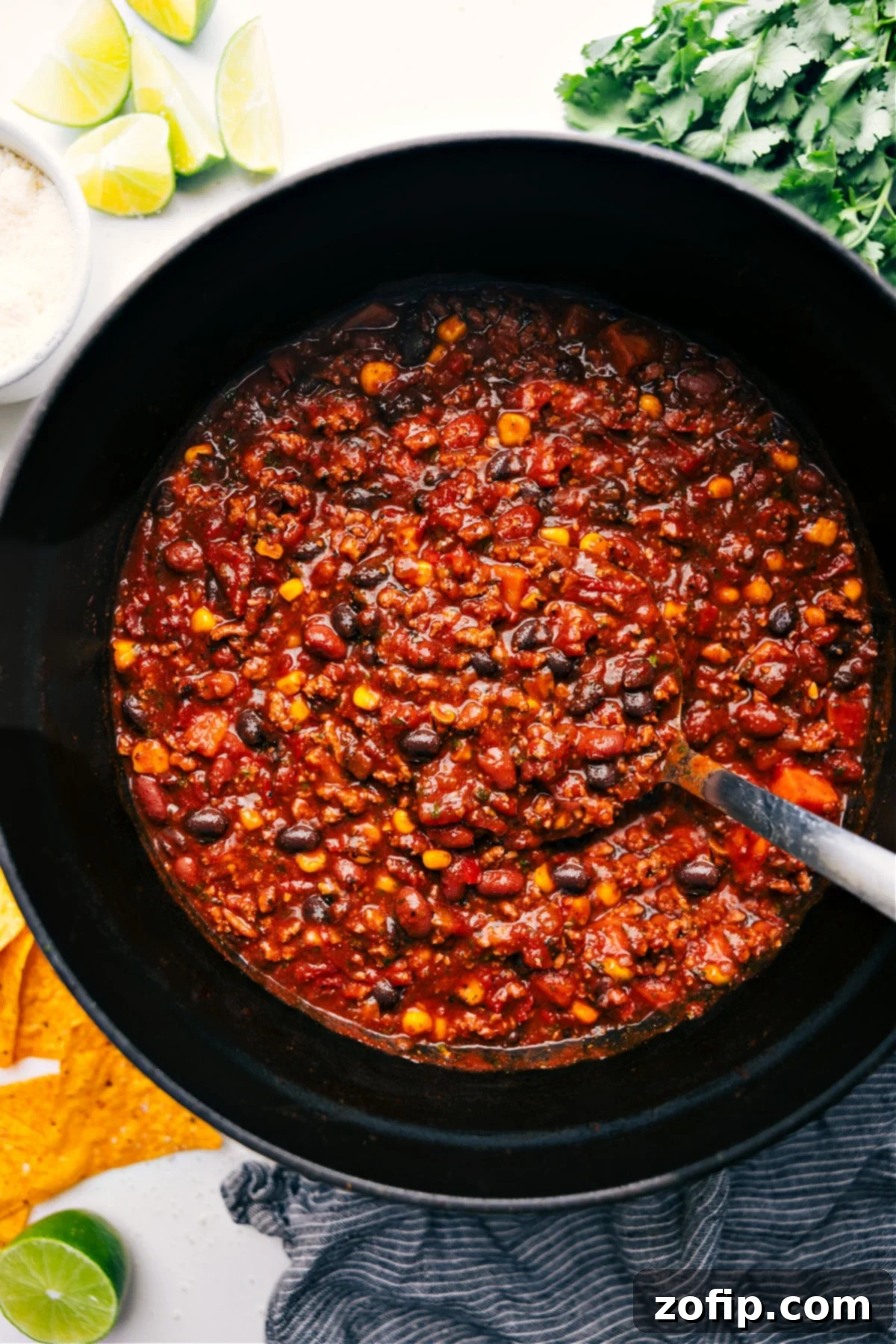 The Best Turkey Chili Recipe A large, rustic pot brimming with rich, hearty Turkey Chili, with a big ladle scooping out a generous portion. The chili is vibrant with chunks of turkey, beans, corn, and sweet potatoes, garnished with fresh cilantro, ready to be served.