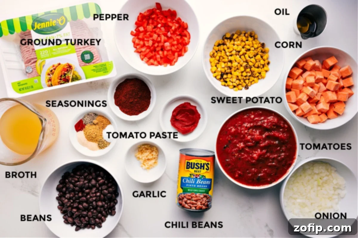 Ingredients In Turkey Chili Recipe A vibrant display of fresh ingredients prepped and ready for the Turkey Chili recipe: lean ground turkey, rich broth, assorted beans (black, kidney, pinto), a variety of aromatic seasonings, minced garlic, concentrated tomato paste, crisp bell pepper, hearty chili beans, sweet diced potato, crushed tomatoes, finely chopped onion, sweet corn, and a bottle of olive oil.