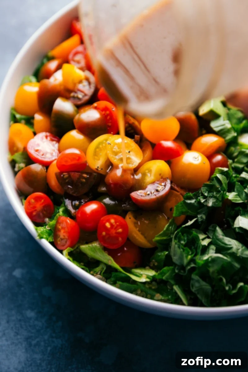 Balsamic dressing being drizzled generously over a vibrant Caprese Quinoa Salad, showcasing fresh ingredients.