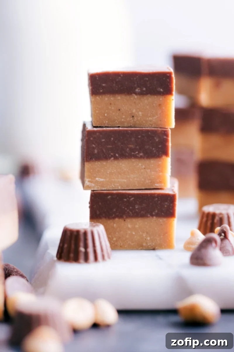 Homemade Reese's Fudge: A two-layered peanut butter and milk chocolate fudge recipe, made easily on the stovetop in under thirty minutes without a candy thermometer. Perfect holiday treat. Image of three irresistible pieces of Reese's Fudge, showcasing the distinct peanut butter and chocolate layers.