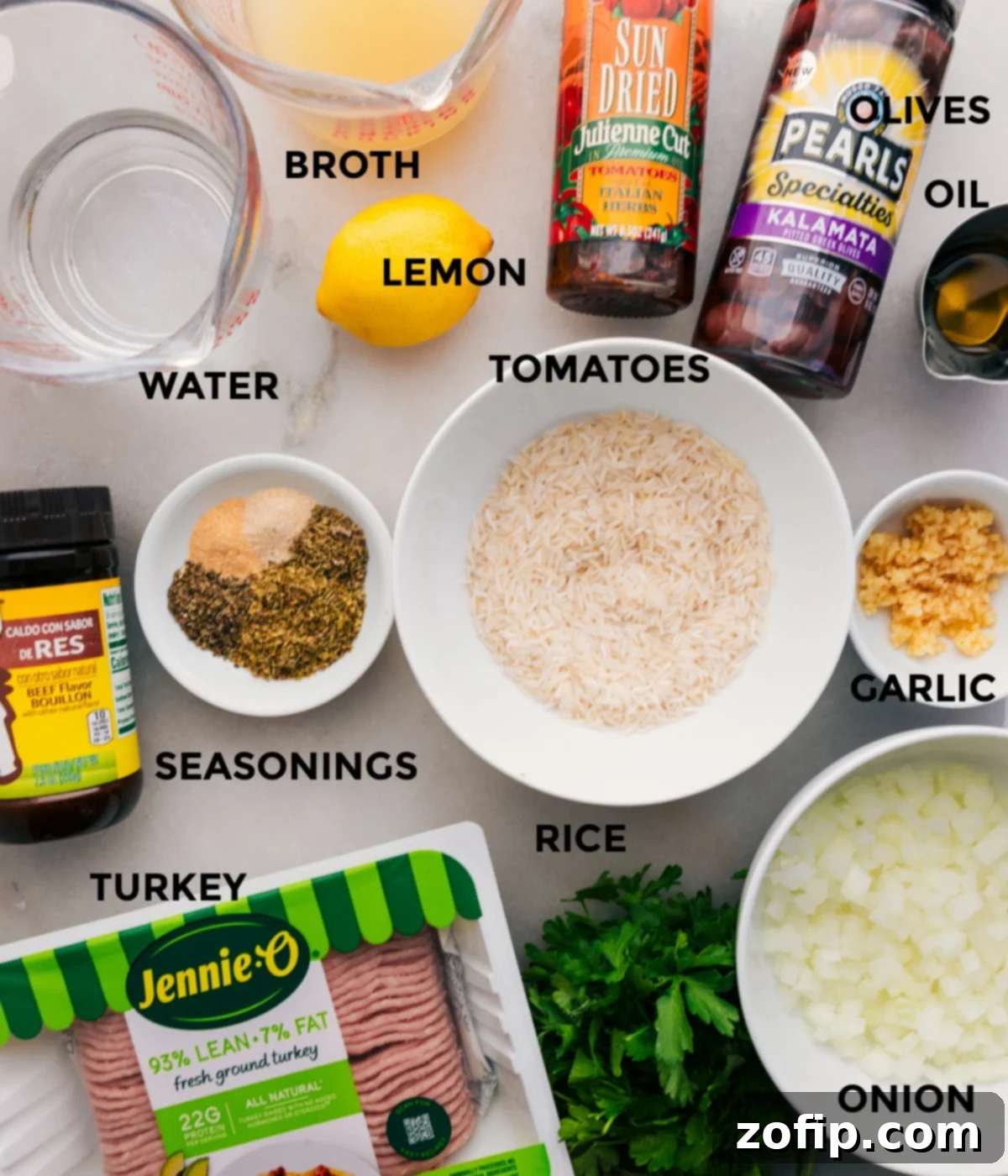 Essential Ingredients for Greek Ground Turkey A selection of fresh and prepped ingredients for Greek Ground Turkey bowls, including rice, various vegetables, ground turkey, herbs, spices, olives, sun-dried tomatoes, olive oil, broth, water, and lemons.