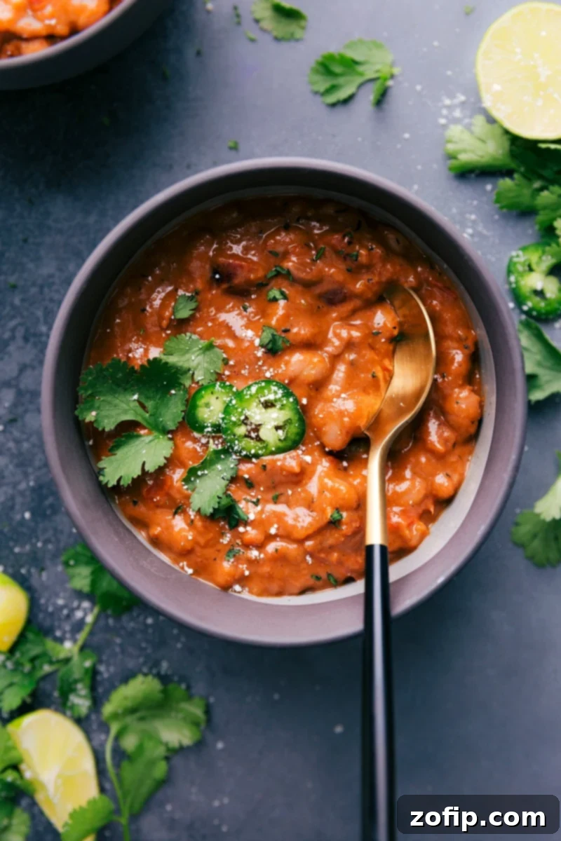 You won't believe how simple these from-scratch Pinto Beans are -- no soaking required! These beans are deeply savory with a smoky flavor and have the best creamy texture! Recipe via ChelseasMessyApron.com #pintos #pintobeans #instantpot #crockpot #slowcooker #nosoak #easy Overhead image of the creamy, smoky pinto beans served in a rustic bowl, ready to be enjoyed.
