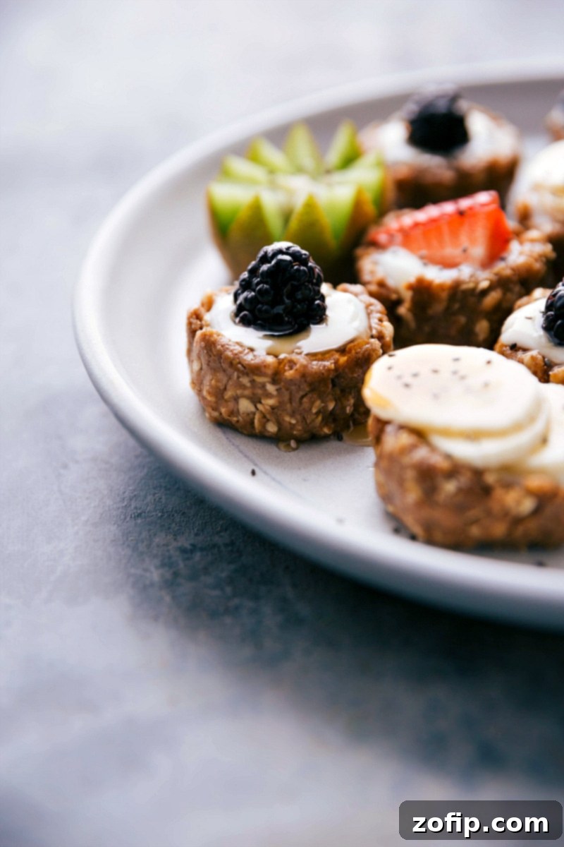 Close-up of a plate featuring several healthy fruit tarts, highlighting the texture of the no-bake crust and the freshness of the fruit toppings.