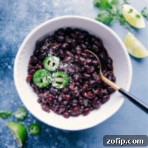 A bowl of delicious homemade black beans, garnished with fresh herbs and a lime wedge, ready to be served.